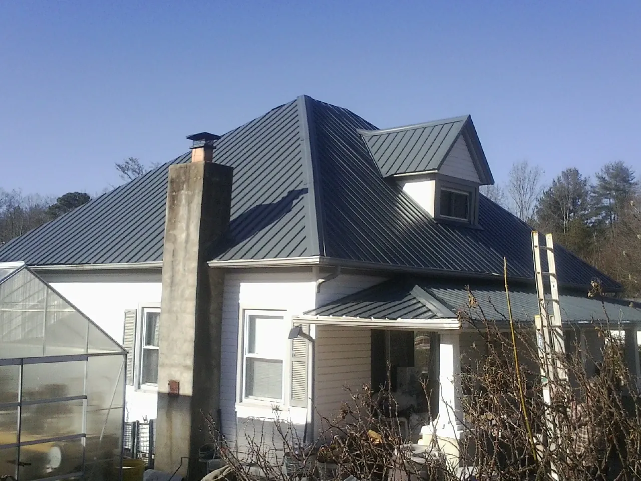 Dark blue standing seam metal roof on a white farmhouse with dormer — Slate & Tile Roof Repair by Roofing Brothers in Bath