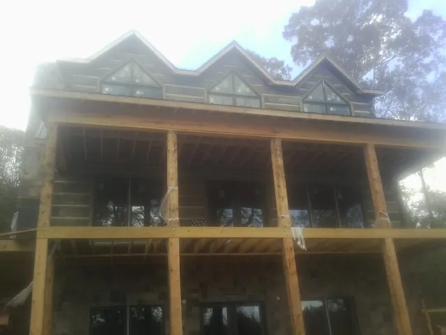 Dormers and porch framing on a large log home under construction — Roof Coating work by our crew in Bath