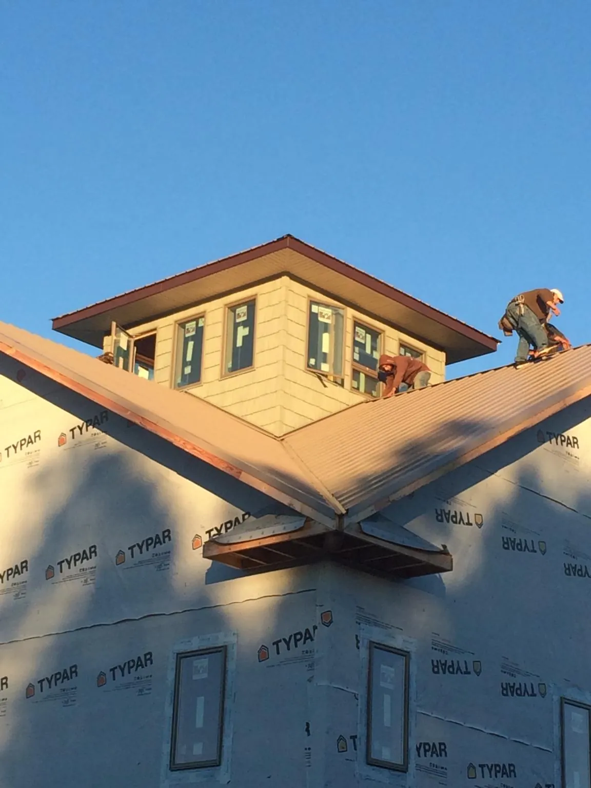 Roofers working around a rooftop cupola on a new metal roof at sunset — Roof Waterproofing in Bath by Roofing Brothers